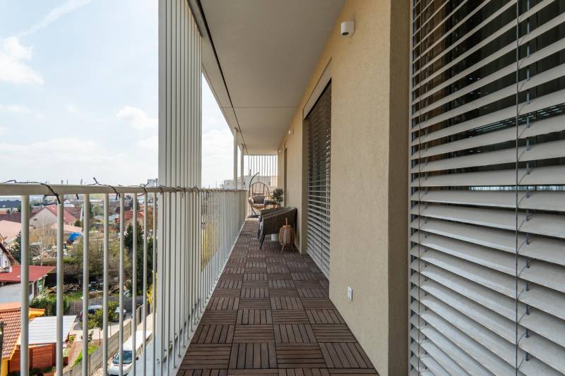 A balcony with a wooden decor floor in a 3-room apartment, view of Bratislava - Ružinov.