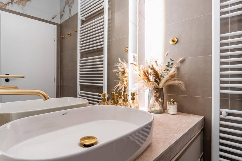 A bathroom with gold details and decoration in a 3-room apartment.