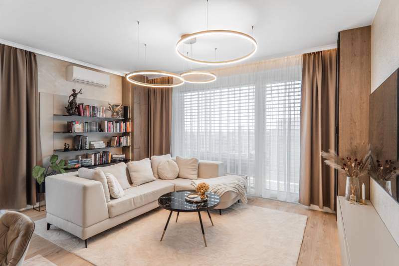 Living room with wood-patterned flooring in a 3-room apartment, comfortable sofa, bookshelf.