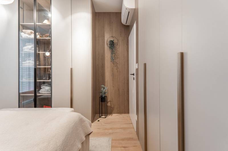 A cozy bedroom with a wood-patterned floor and a glass wardrobe in a 3-room apartment.