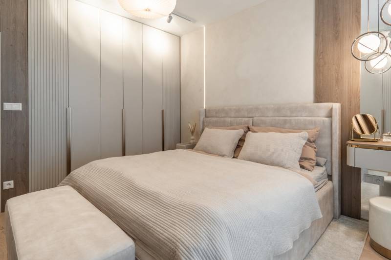 A bright bedroom with a built-in wardrobe and a bed in a 3-room apartment.