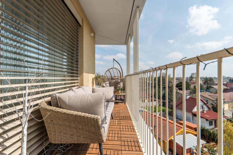 A balcony of a 3-room apartment in Bratislava - Ružinov with outdoor seating and wooden decor.