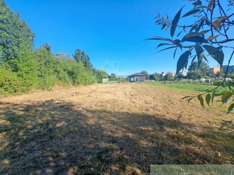 A residential plot surrounded by greenery in Hosťová under sunny weather.