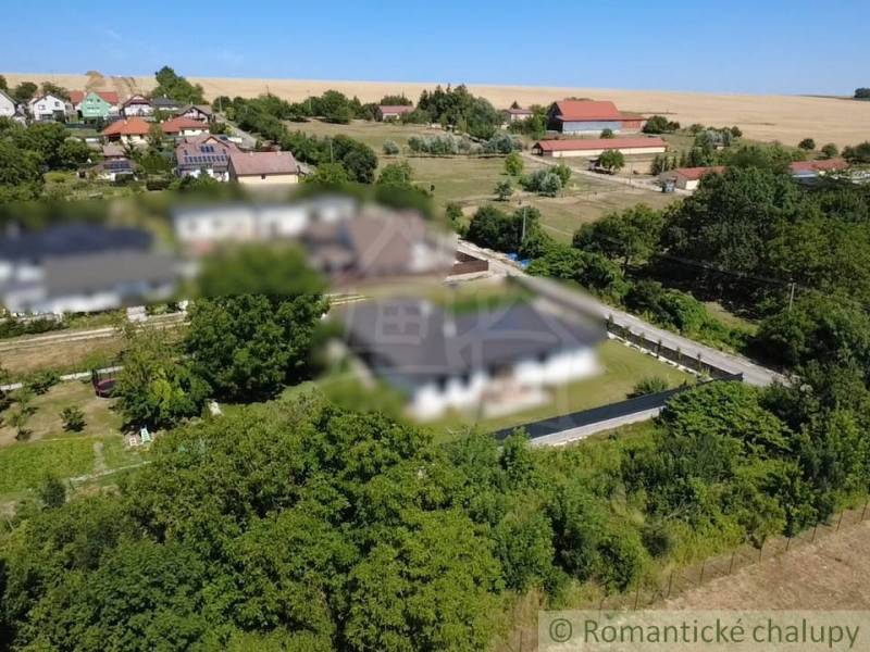 Panoramic view of plots - housing in the village of Hosťová surrounded by greenery and houses.
