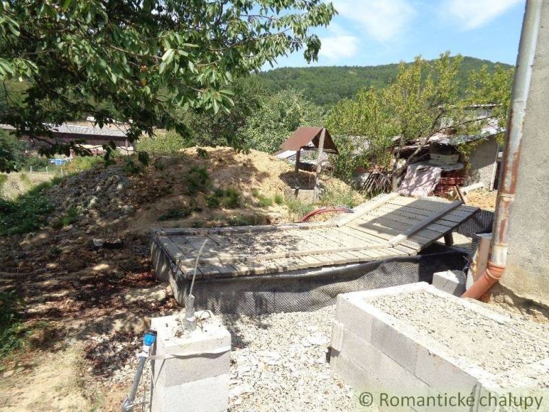 The backyard of a family house in Šiatorská Bukovinka with a pile of soil and trees.