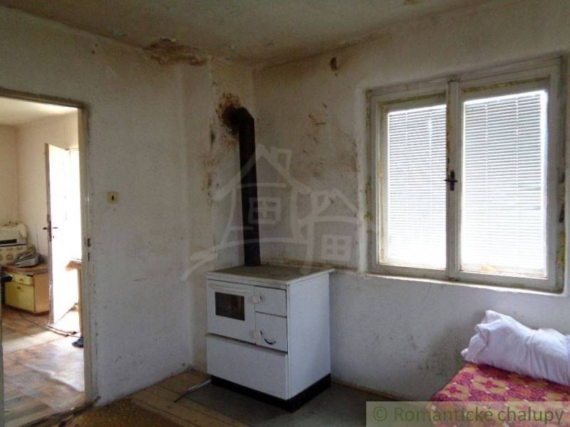 A room in a family house with a tiled stove and worn-out walls.