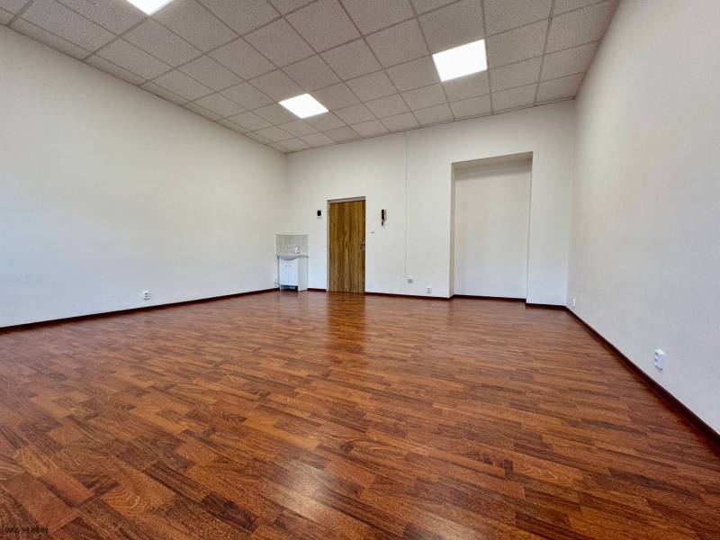 An office with a wooden decor floor, white walls, and a suspended ceiling.
