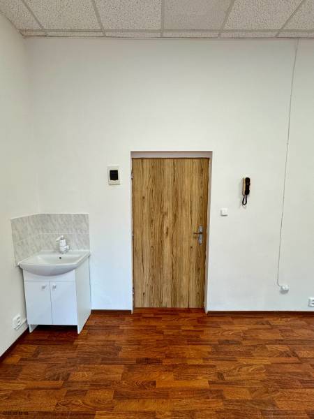 Floor with wood decor, sink, door, and ceiling tiles in the office.