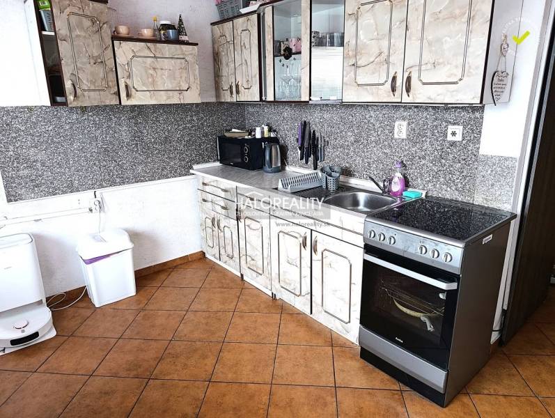 A kitchen with tiles and a kitchen unit in a 2-room apartment.