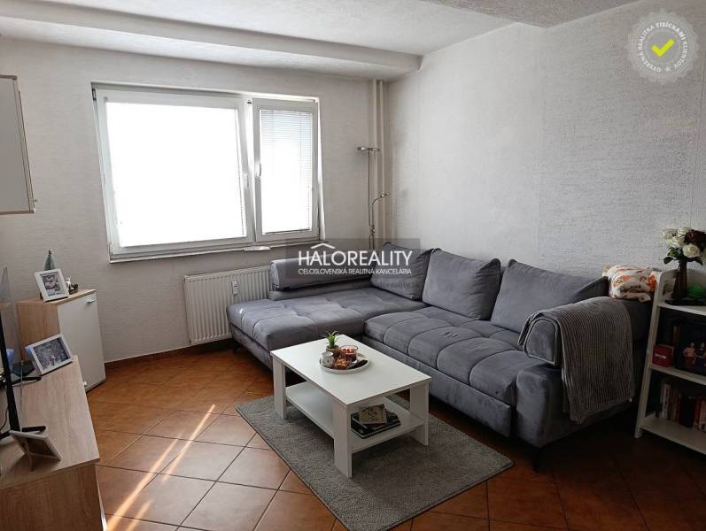Living room of a two-room apartment with a corner sofa and a coffee table on a floor with a wooden decor.