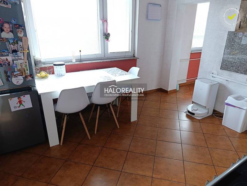 Dining room in a 2-room apartment with a white table and brown floor.
