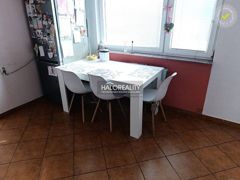 Kitchen of a 2-room apartment with a dining table, white chairs, and a window.