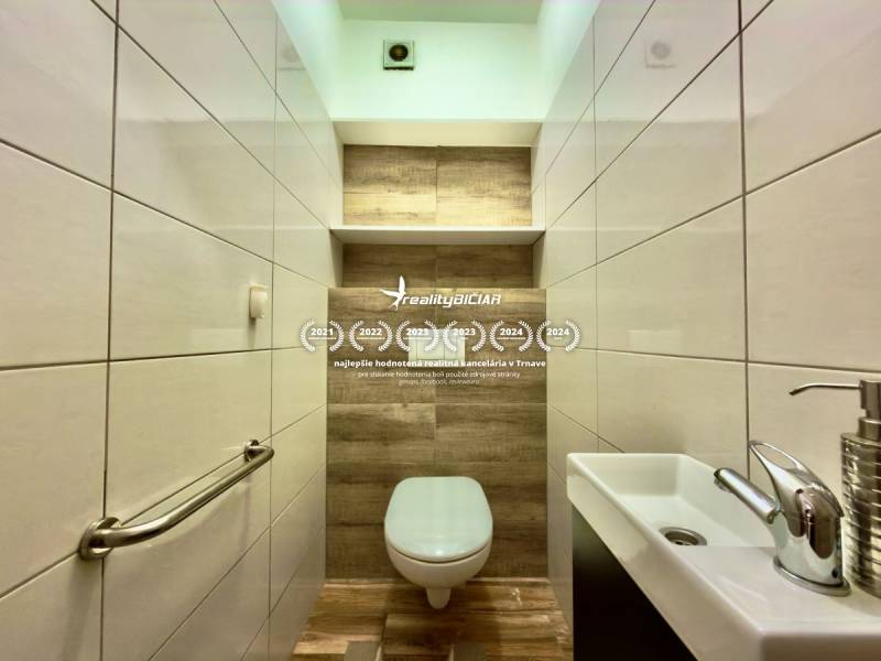 Bathroom in a 2-room apartment with a wooden decor floor and white tiles.