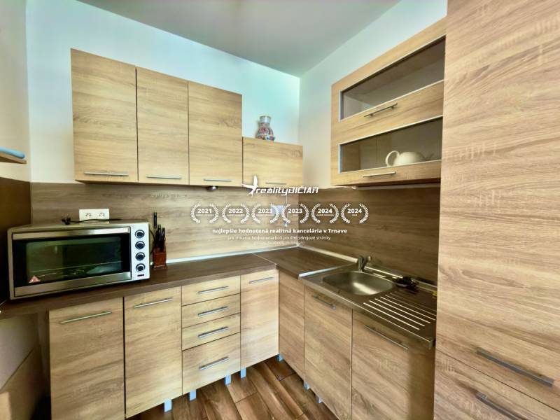 A kitchen with built-in cabinets and a wooden decor floor in a 2-room apartment.