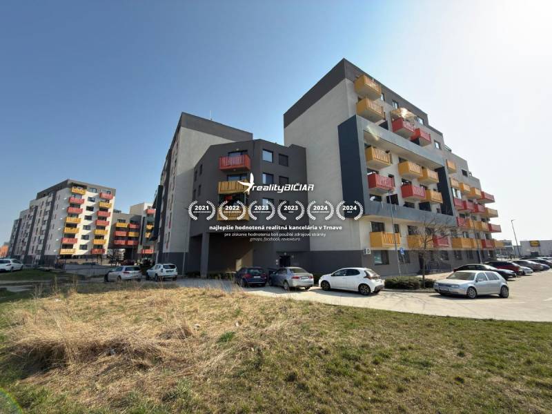 Apartment buildings on Mikovíniho Street in Trnava with a parking lot and green area.