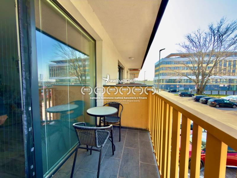 The balcony of a 2-room apartment on Mikovíniho Street in Trnava with seating and a view of the street.