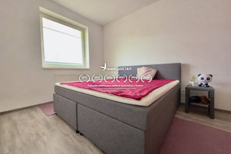 Bedroom in a 2-room apartment with a bed, wood-patterned floor, and a nightstand.