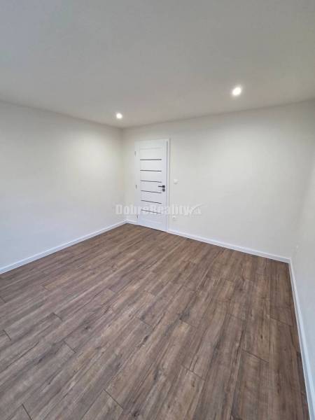 A room in a 3-room apartment with white walls and a wooden decor floor.
