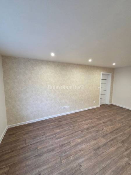 A room with white walls, a wooden decor floor, and built-in lights in a 3-room apartment.