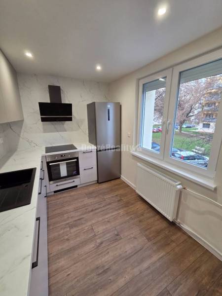A kitchen in a 3-room apartment with white cabinets and a wood-patterned floor.