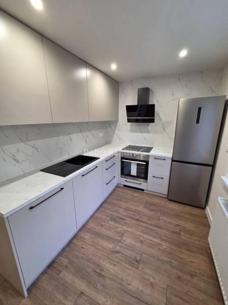 A kitchen with glossy cabinets and a wooden decor floor in a 3-room apartment.