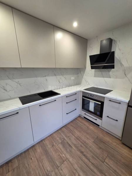 A kitchen with white cabinets and a wood-patterned floor in a 3-room apartment.