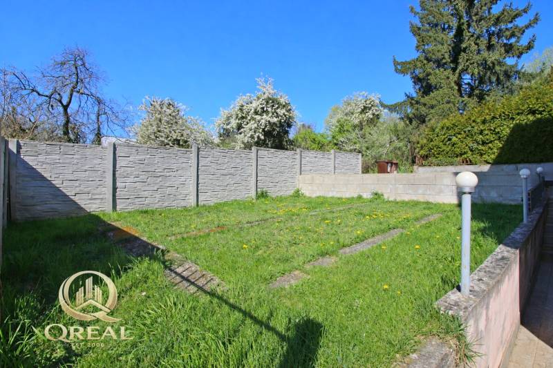 A garden by the house with a lawn, a modern fence, and lights on Boskovičova Street in Bratislava.