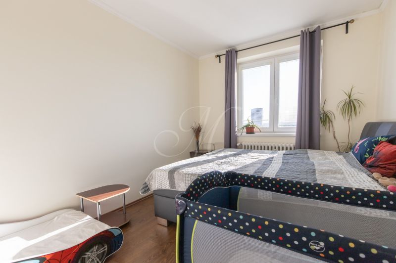 A bedroom with a bed, a crib, and a wooden decor floor in a two-room apartment.