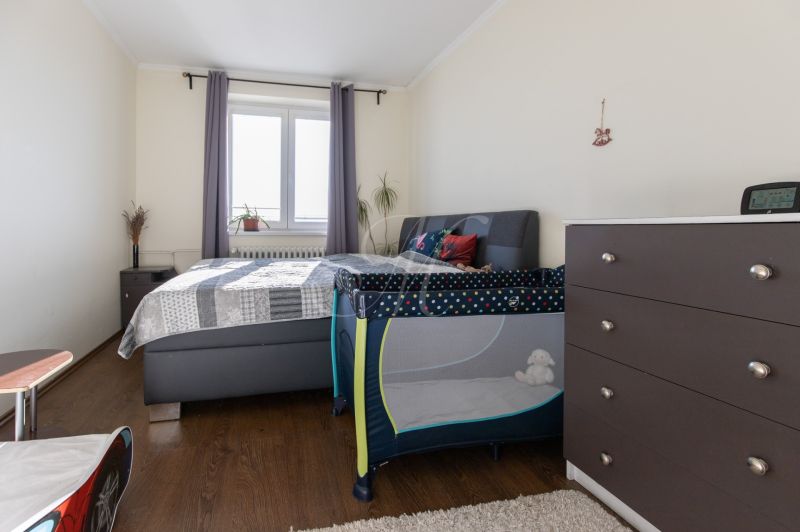Bedroom in a 2-room apartment with a bed, dresser, and baby crib.