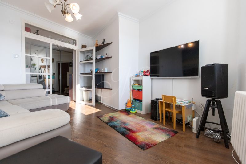 Living room in a two-room apartment with a sofa, TV, children's corner, and floor with wooden decor.