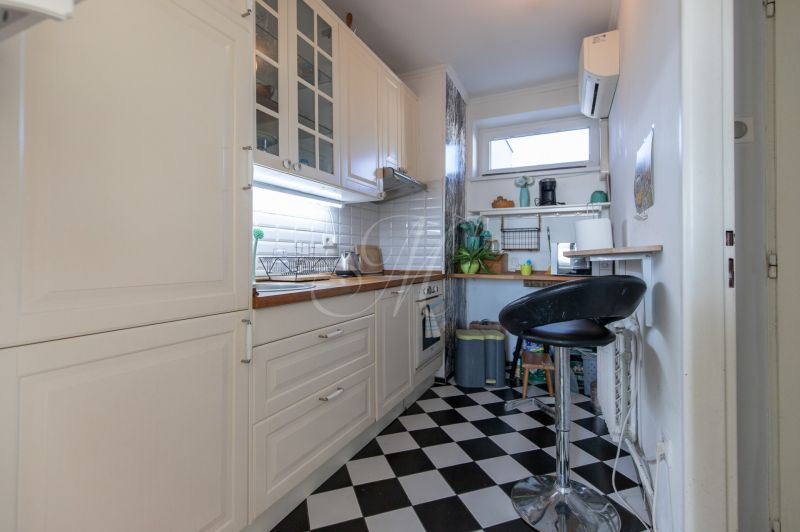 A kitchen in a 2-room apartment with black and white tiles and white cabinets.