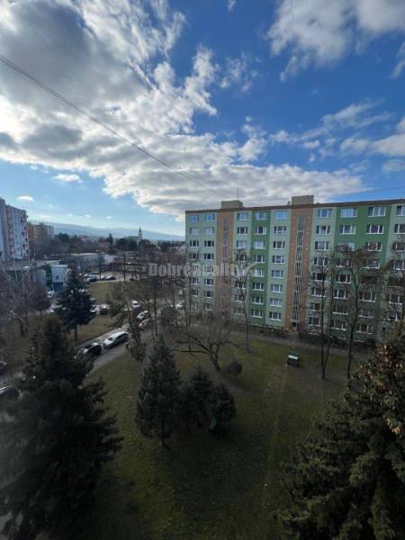 View of the parking lot and greenery near the apartment building on Lúčná Street in Prievidza.