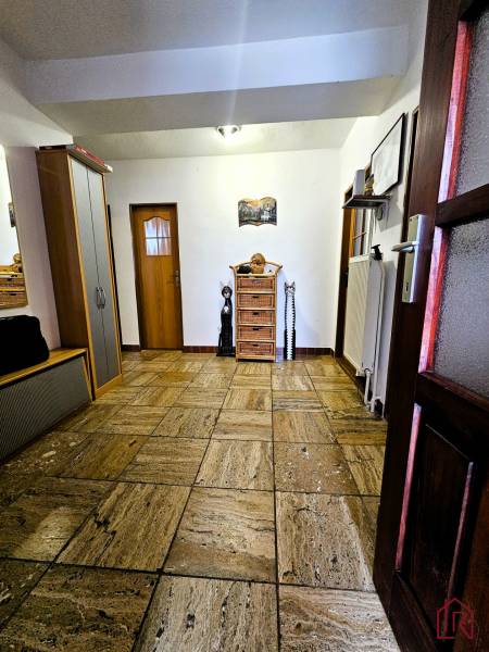 Hallway with ceramic tiles, wooden doors, and a wardrobe in a family house.