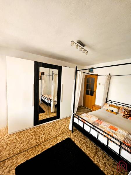 A bedroom in a family house with a bed, a carpet, and a wardrobe with a mirror.