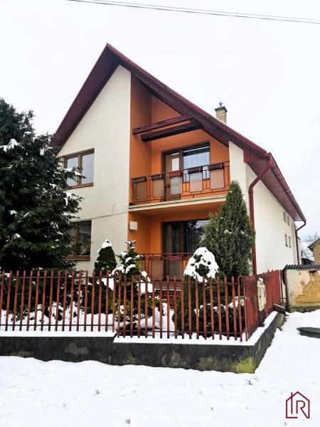 A family house in Kameňany with a snowy yard and a red fence.