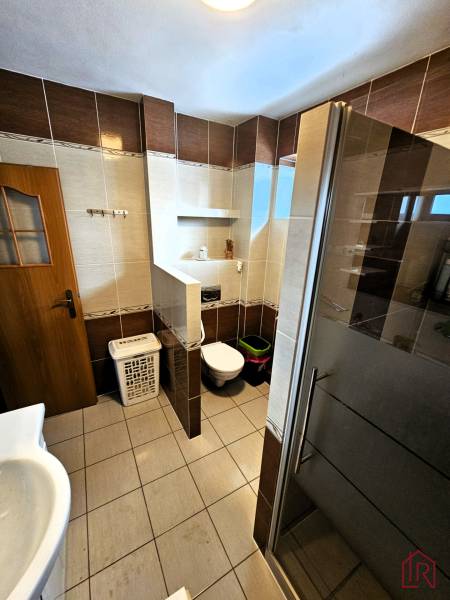 A bathroom in a family house with tiles, a shower, and a toilet.