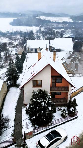 A family house in Kameňany covered with snow, overlooking snow-covered fields and hills.