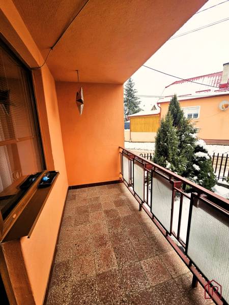 A balcony of a family house in Kameňany with a view of a snowy garden and a tree.