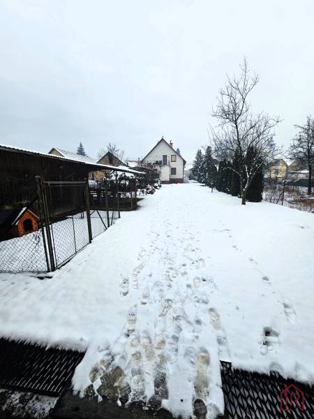 A family house in Kameňany with a snowy yard, surrounded by a garden and trees.