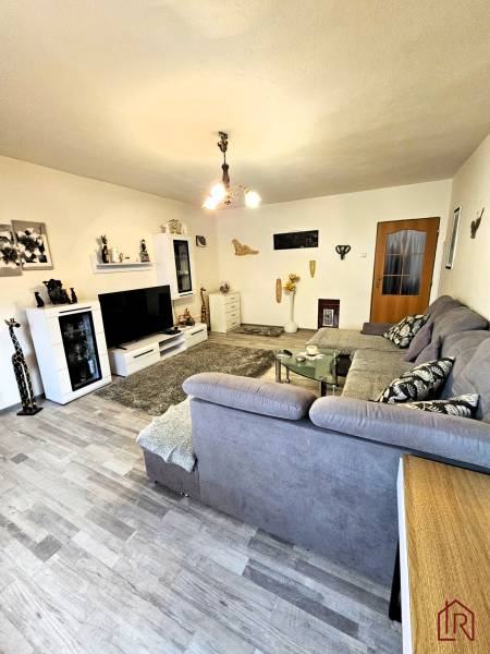 Living room in a family house with a wooden decor floor, gray sofa, and modern lighting.