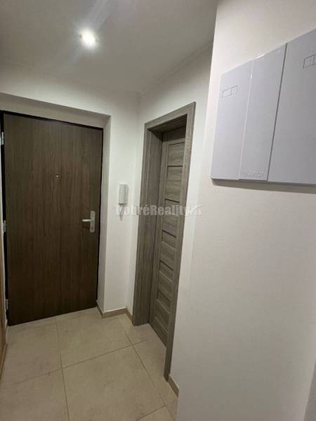Hallway in a 2-room apartment with tiles and wooden doors.