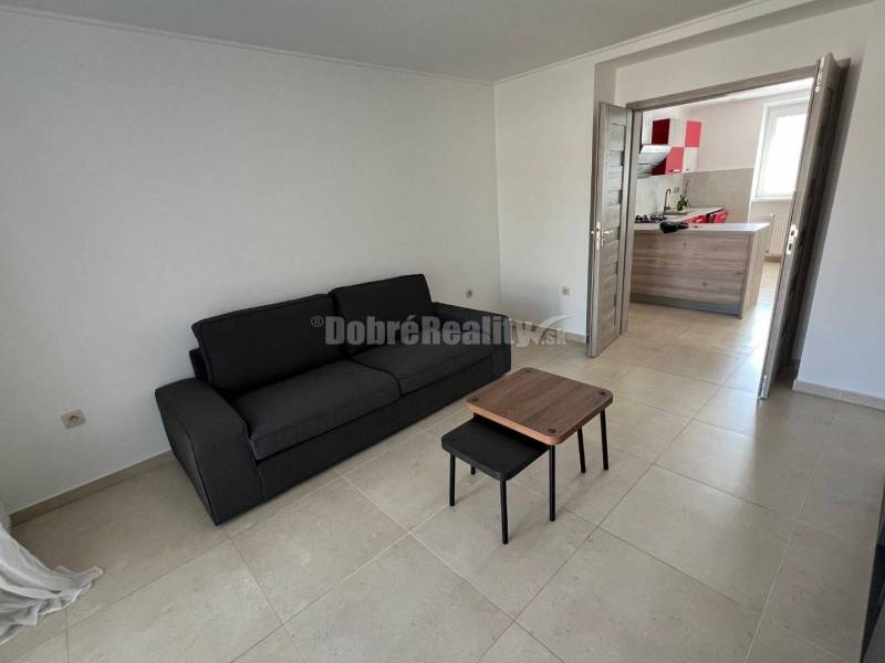 Living room in a two-room apartment with a black sofa and a small table.