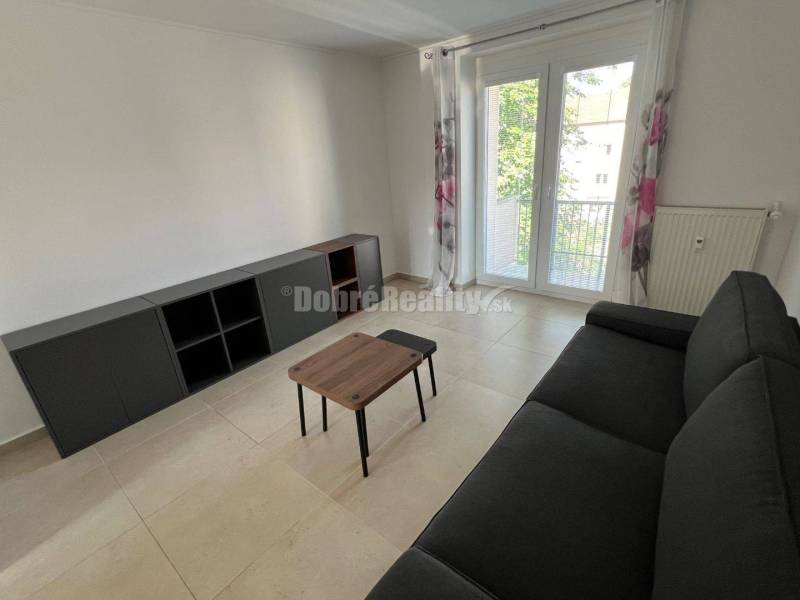 Living room in a two-room apartment with a black sofa and a table.