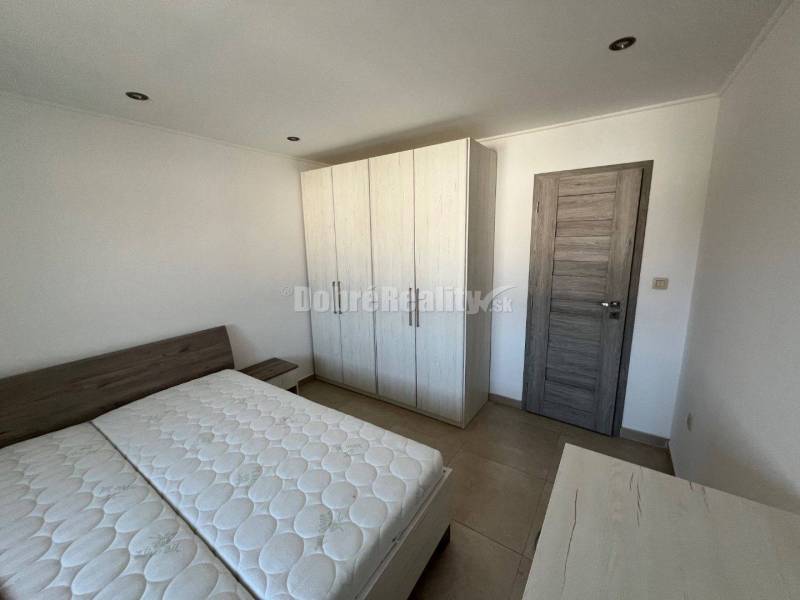 Bedroom in a 2-room apartment with a bed and a wardrobe, floor with wooden decor.