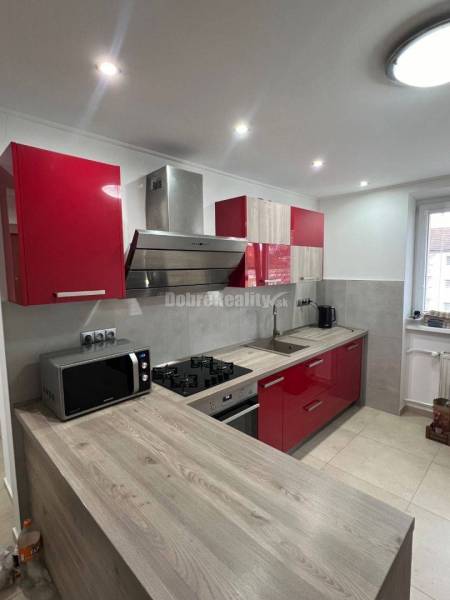 A kitchen in a 2-room apartment with built-in appliances and a floor with a wooden decor.