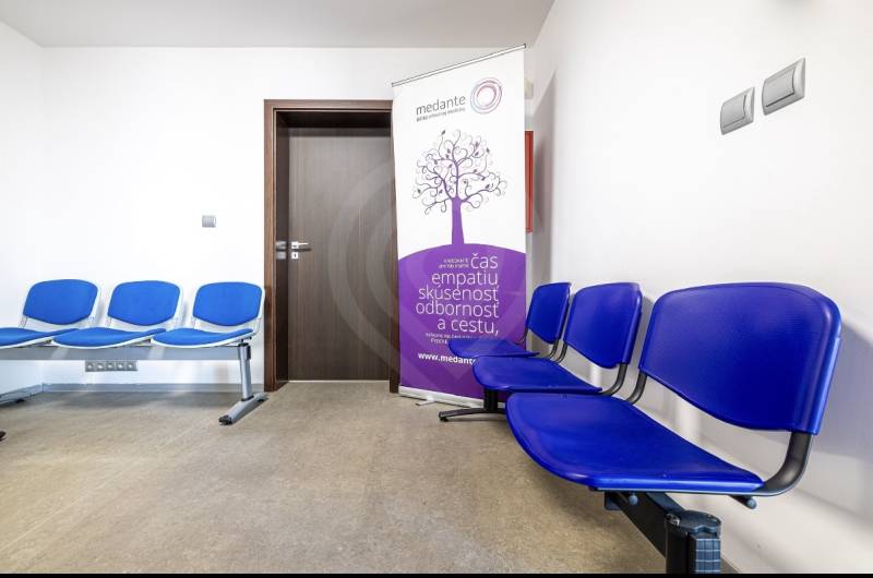 A waiting room in a family house with blue chairs and an advertising banner.