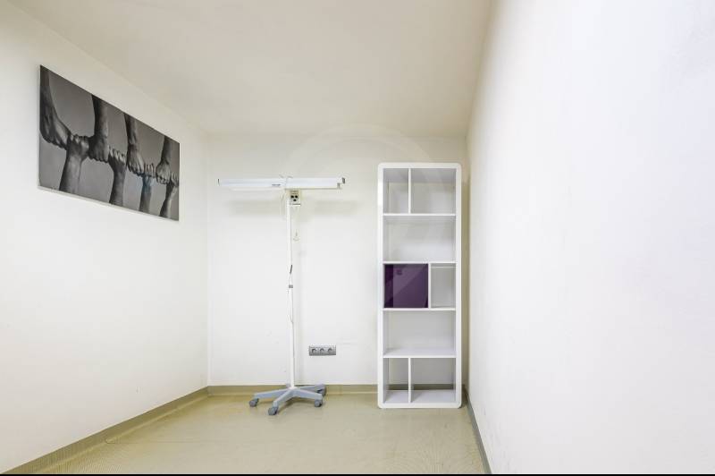 A room with a shelving unit, a lamp stand, and a minimalist painting in a family house.