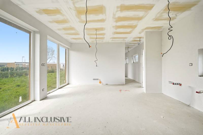 A spacious cottage with white walls and large windows, and a floor with a wooden decor.