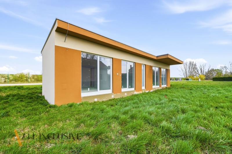 A cottage in Vojka nad Dunajom with a green grass environment and large windows.