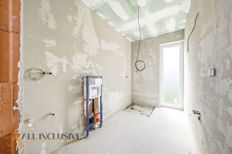 The interior of the cottage with unfinished walls and preparation for the installation of sanitary equipment.